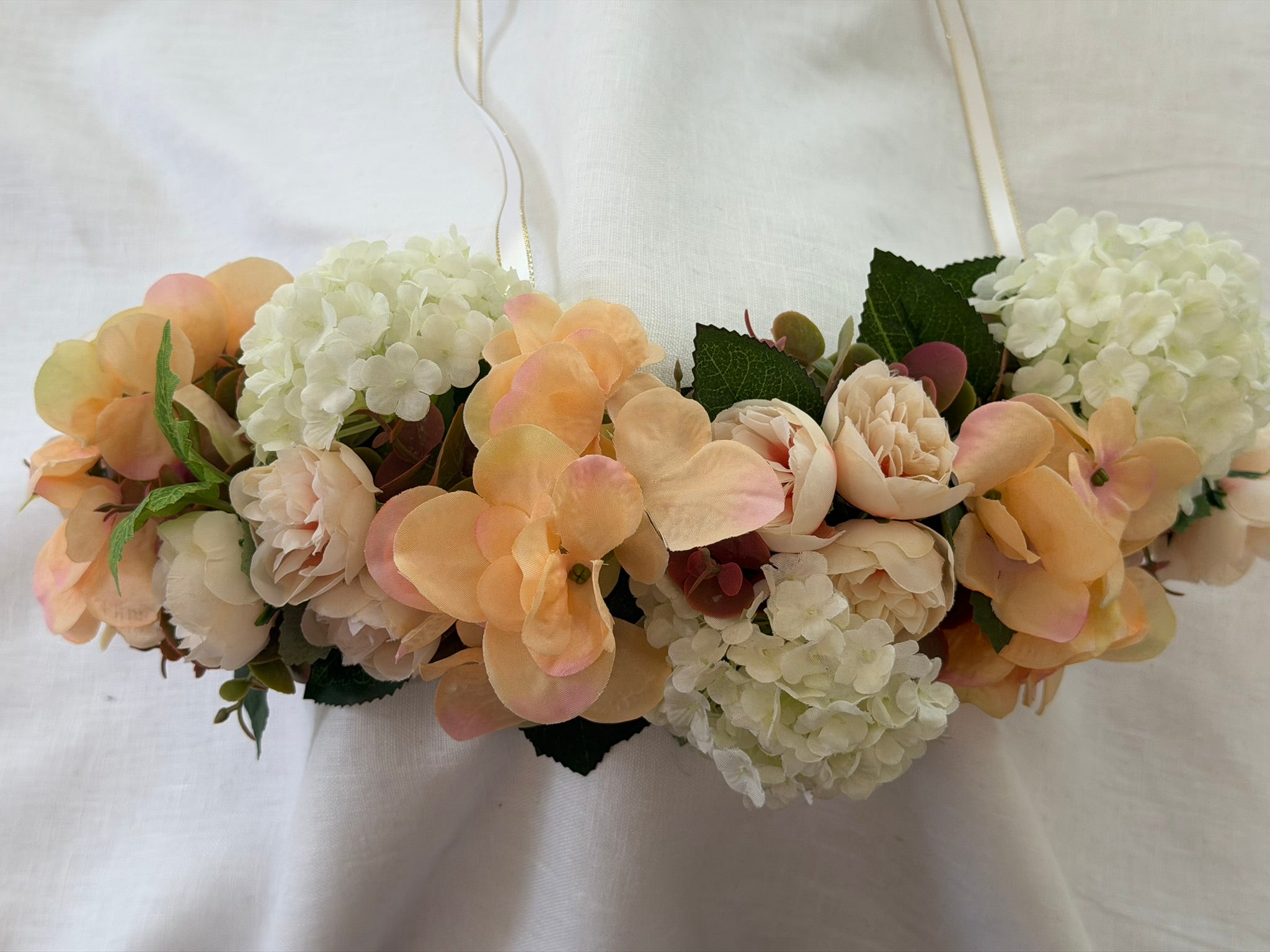 Full, lush floral design Peach hydrangea, ivory hydrangea & blush garden rose blooms Lush green foliage accents Ribbon ties for adjustable, comfortable fit Wear as a flower crown, or drape as a garland Suitable for adults, children & pets. Perfect for weddings, garden parties, hens celebrations, festivals, and photoshoots