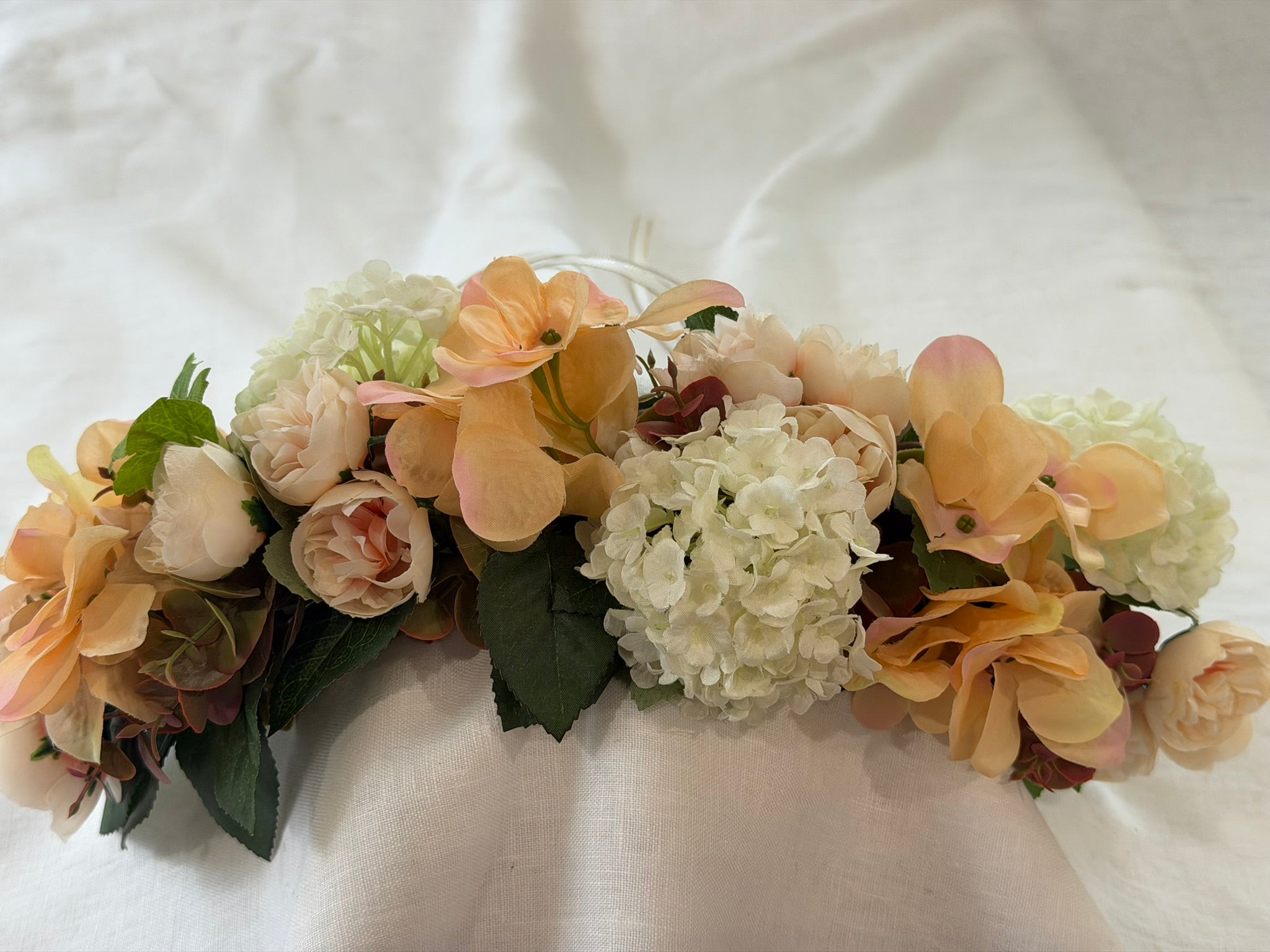 Full, lush floral design Peach hydrangea, ivory hydrangea & blush garden rose blooms Lush green foliage accents Ribbon ties for adjustable, comfortable fit Wear as a flower crown, or drape as a garland Suitable for adults, children & pets. Perfect for weddings, garden parties, hens celebrations, festivals, and photoshoots