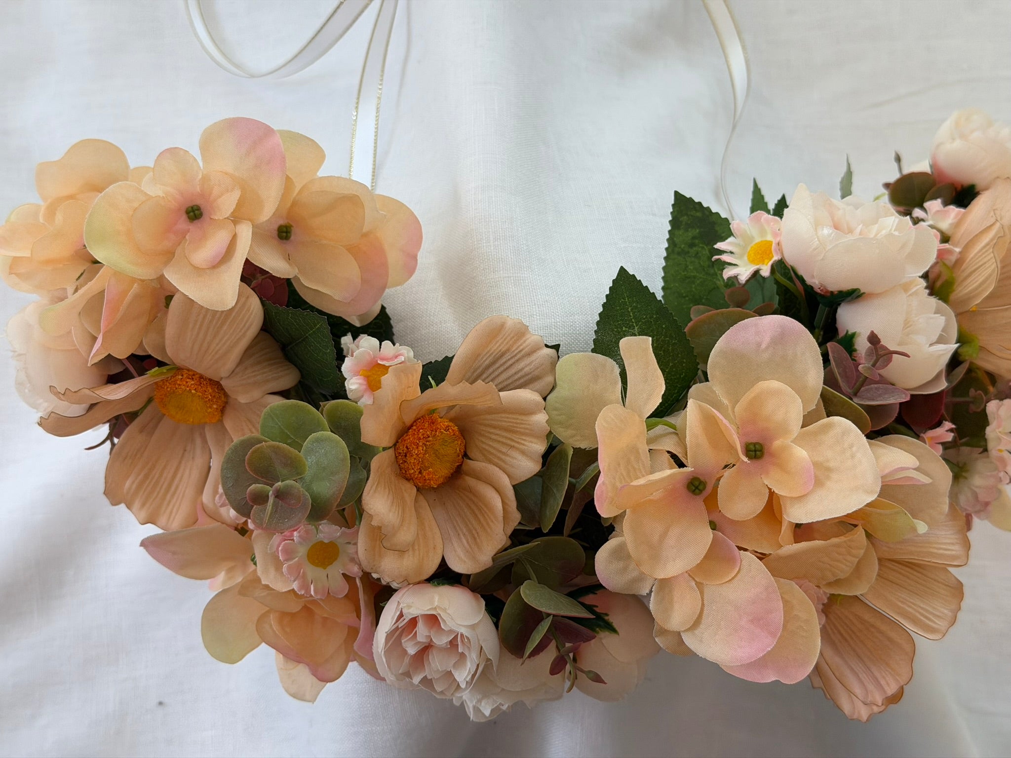 Full, lush floral design Peach hydrangea, cosmos, ranunculus, and daisy blooms Lush eucalyptus foliage accents Ribbon ties for adjustable, comfortable fit Wear as a flower crown, or as a garland around your dog's neck Suitable for adults, children and pets Perfect for weddings, garden parties, hens celebrations, festivals, and photoshoots