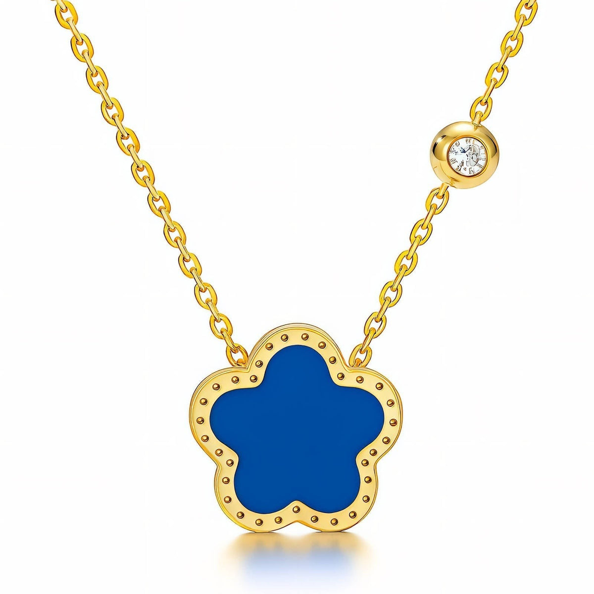 The Velvet Grove floral pendant necklace featuring a deep blue flower charm in a gold-tone frame with a crystal accent.