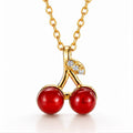 The Velvet Grove cherry pendant necklace featuring two glossy red beads and crystal-accented gold-tone stems on a chain.