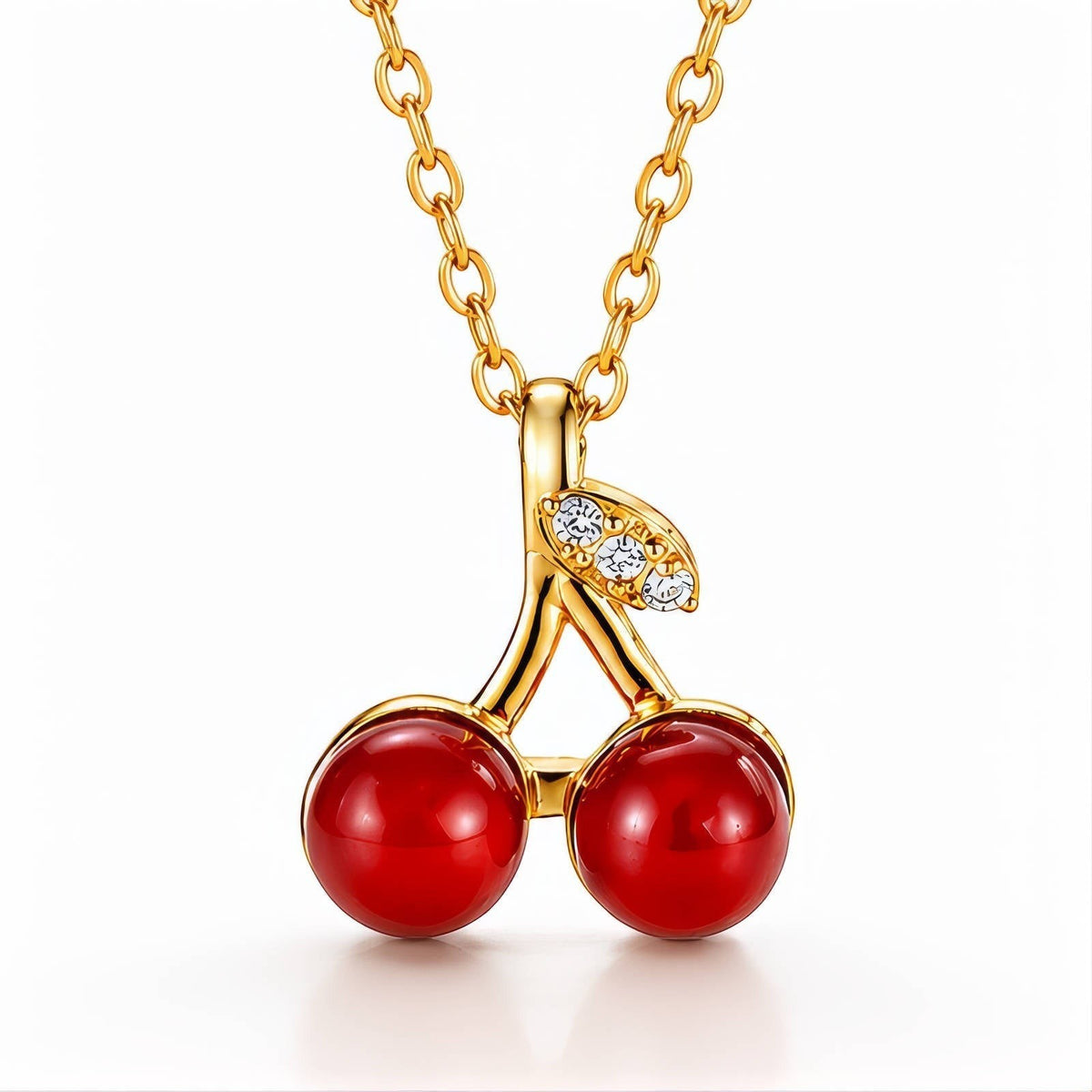 The Velvet Grove cherry pendant necklace featuring two glossy red beads and crystal-accented gold-tone stems on a chain.