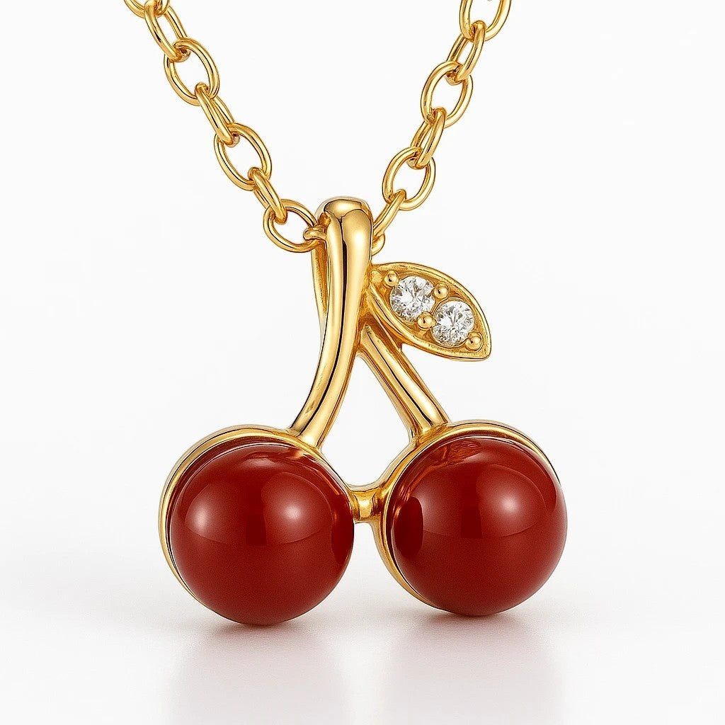 The Velvet Grove cherry pendant necklace with deep red glossy beads and crystal-accented gold stem on a gold chain.