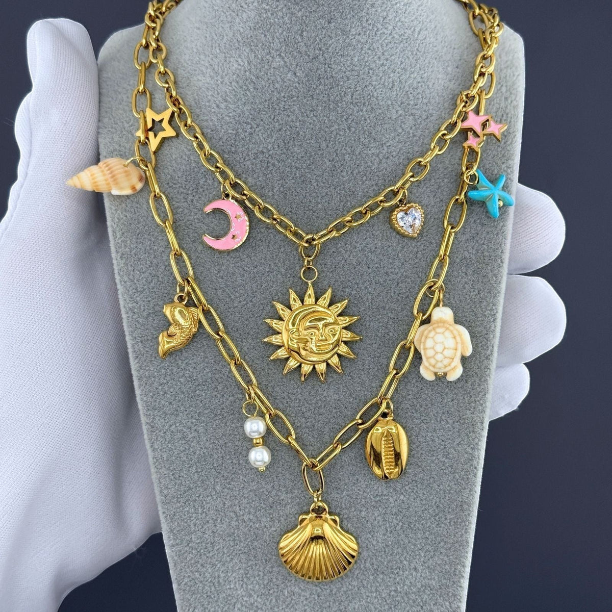 The Velvet Grove gold-tone layered necklace featuring coastal charms like a seashell, starfish, turtle, and sun pendant.