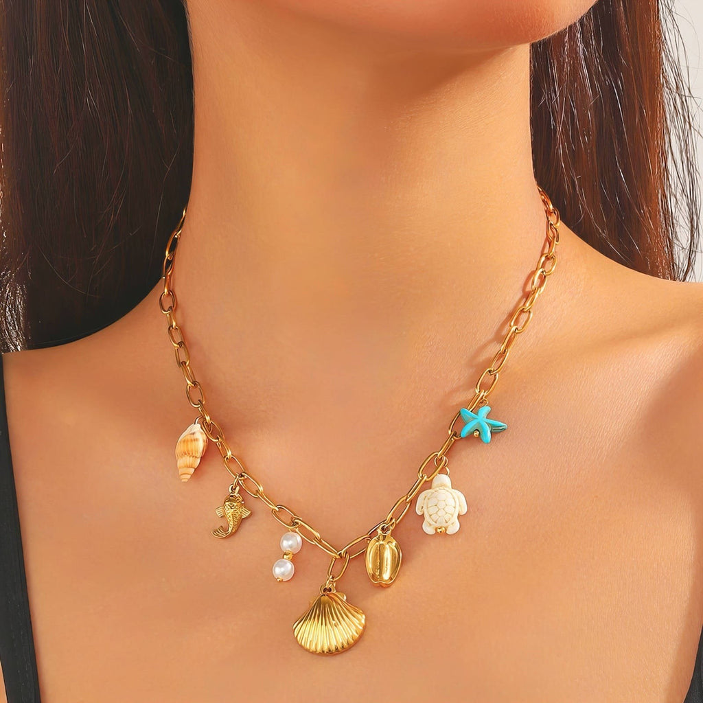 The Velvet Grove gold-tone link necklace featuring coastal charms including a seashell, starfish, turtle, and pearls.