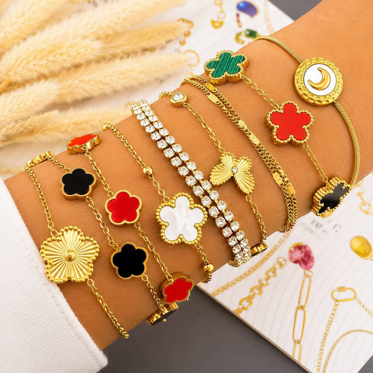 The Velvet Grove gold-tone chain bracelet stack featuring red, black, white, and green floral motif charms.