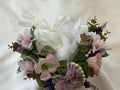 The Velvet Grove floral crown with pink and purple faux flowers, green foliage, and pearls with white ribbon ties.
