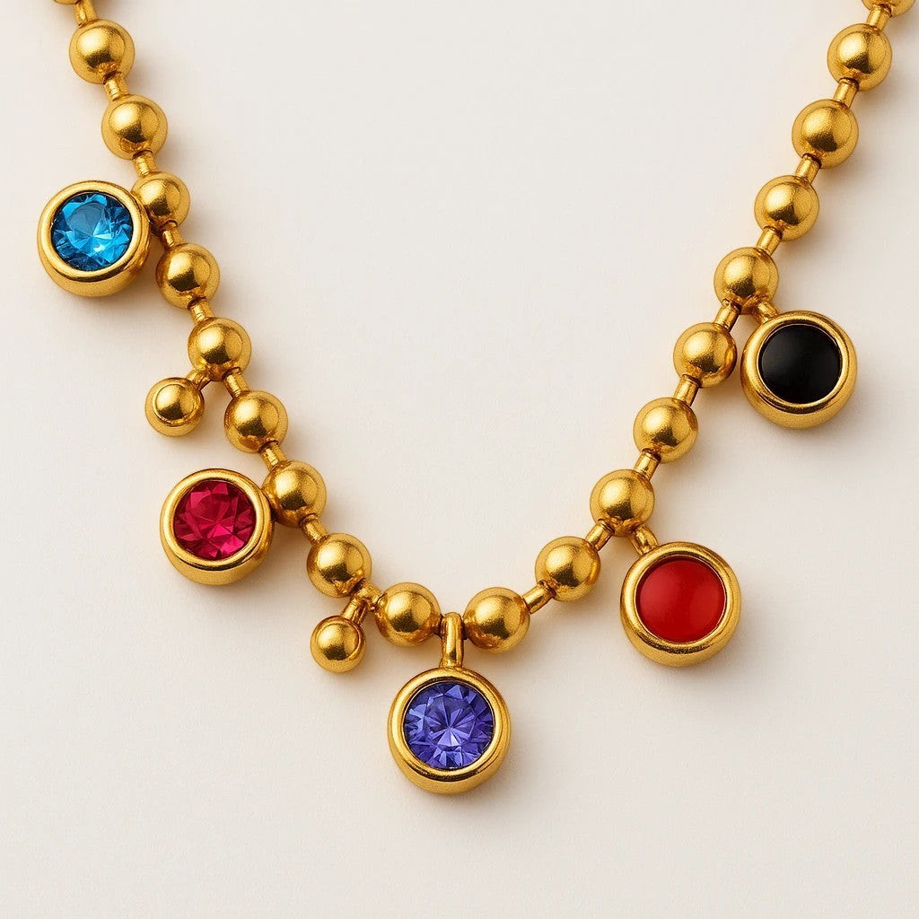 The Velvet Grove gold-tone ball chain necklace featuring bezel-set multi-colored crystal charms in a close-up view.