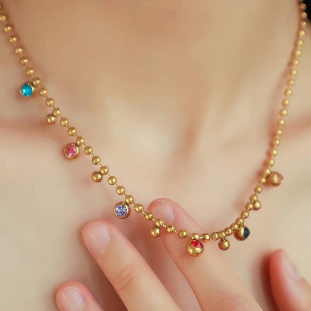 The Velvet Grove gold-tone beaded chain necklace featuring scattered multi-colored bezel-set crystal accents.