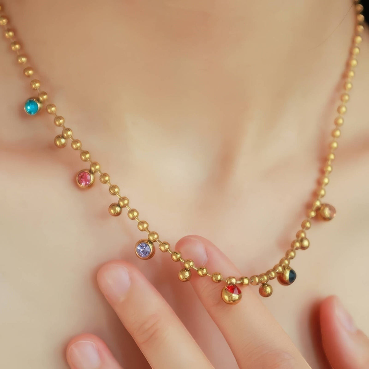 The Velvet Grove gold-tone beaded chain necklace featuring scattered multi-colored bezel-set crystal accents.