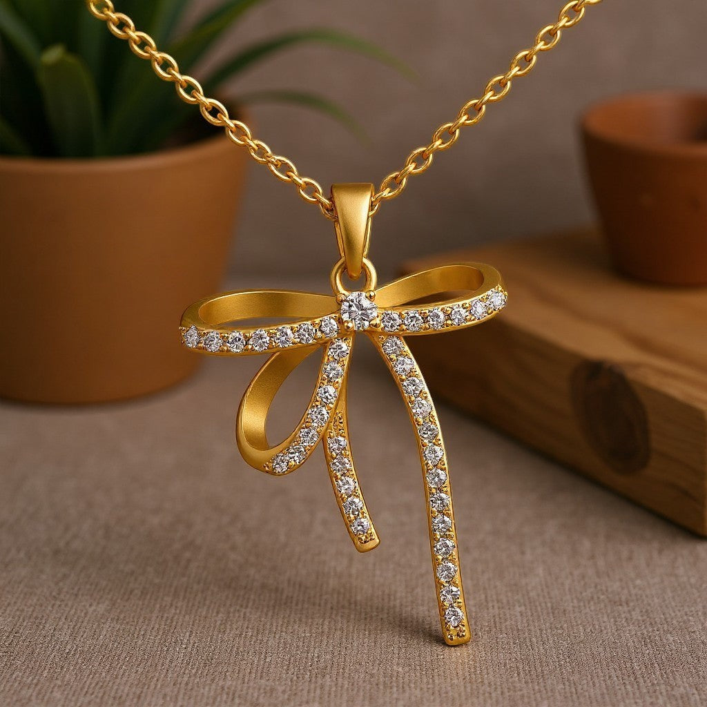 The Velvet Grove gold-tone bow pendant necklace featuring shimmering cubic zirconia stones on a delicate chain.