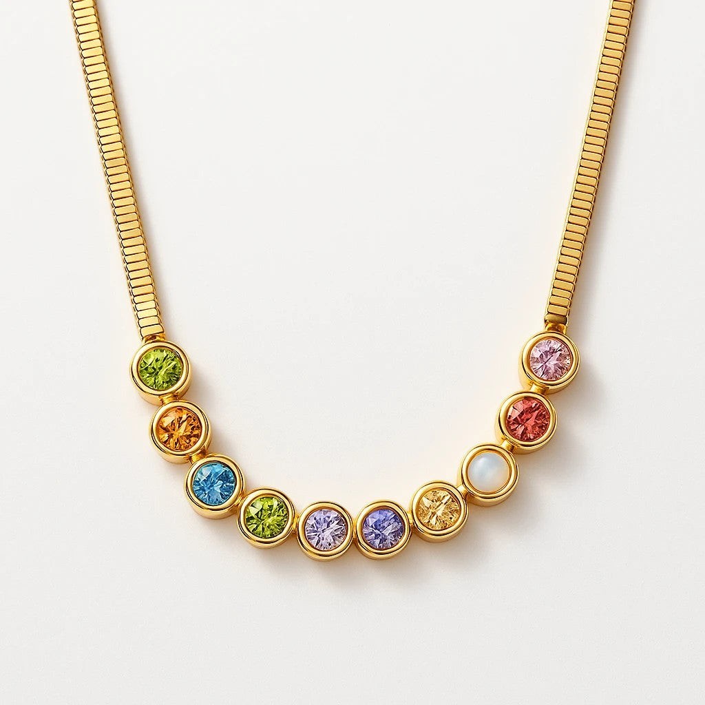 The Velvet Grove gold-tone herringbone chain necklace featuring a row of vibrant, bezel-set multi-colored stones.