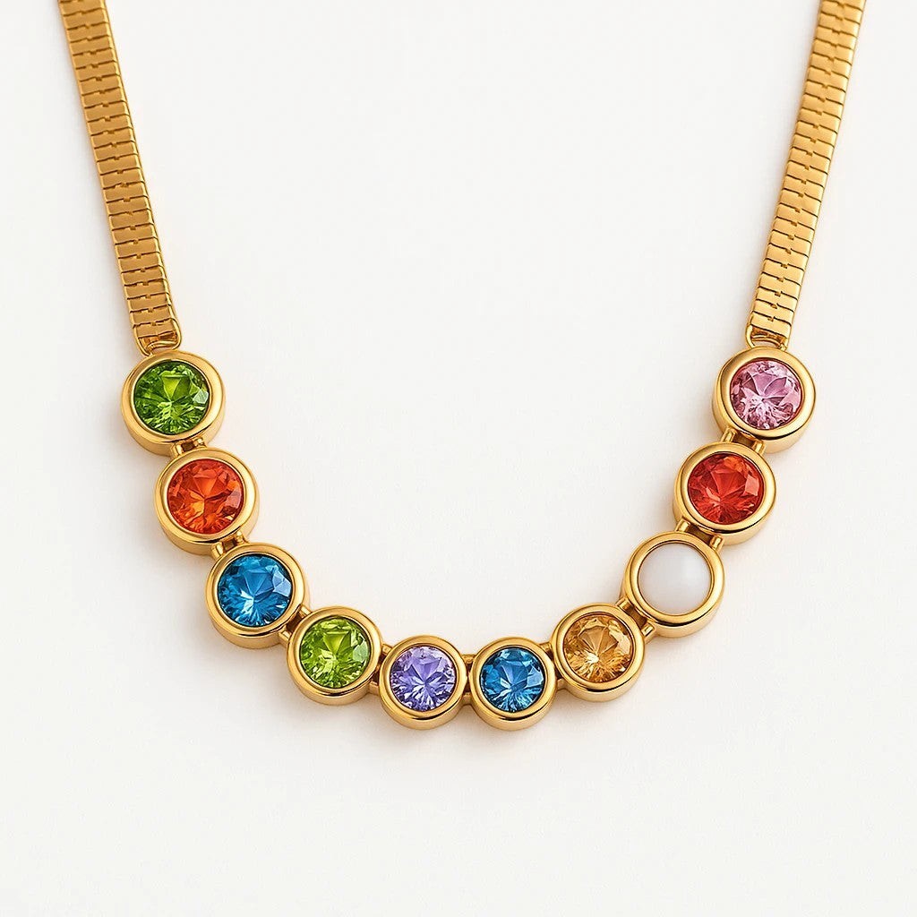 The Velvet Grove gold-tone herringbone chain necklace featuring a row of vibrant, bezel-set multi-colored stones.