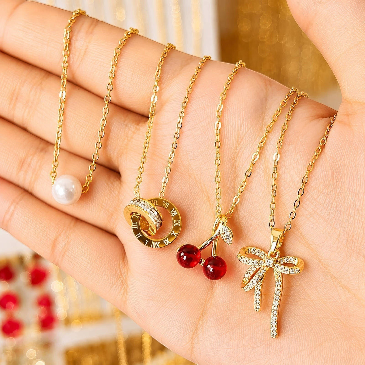 The Velvet Grove gold-tone necklace set featuring a cherry pendant with crystals, a pearl, Roman numeral ring, and bow.