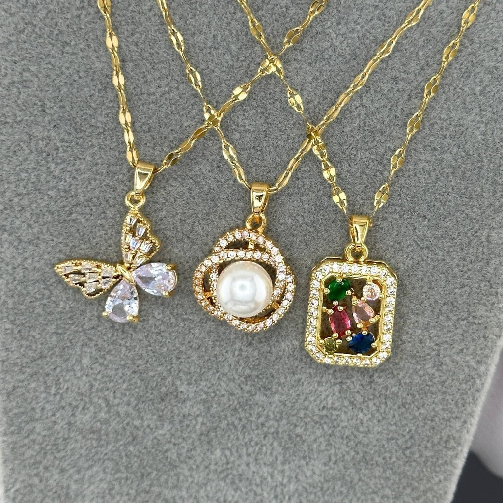 The Velvet Grove gold-toned pendant necklace set featuring a butterfly, pearl, and multi-colored gemstone design.