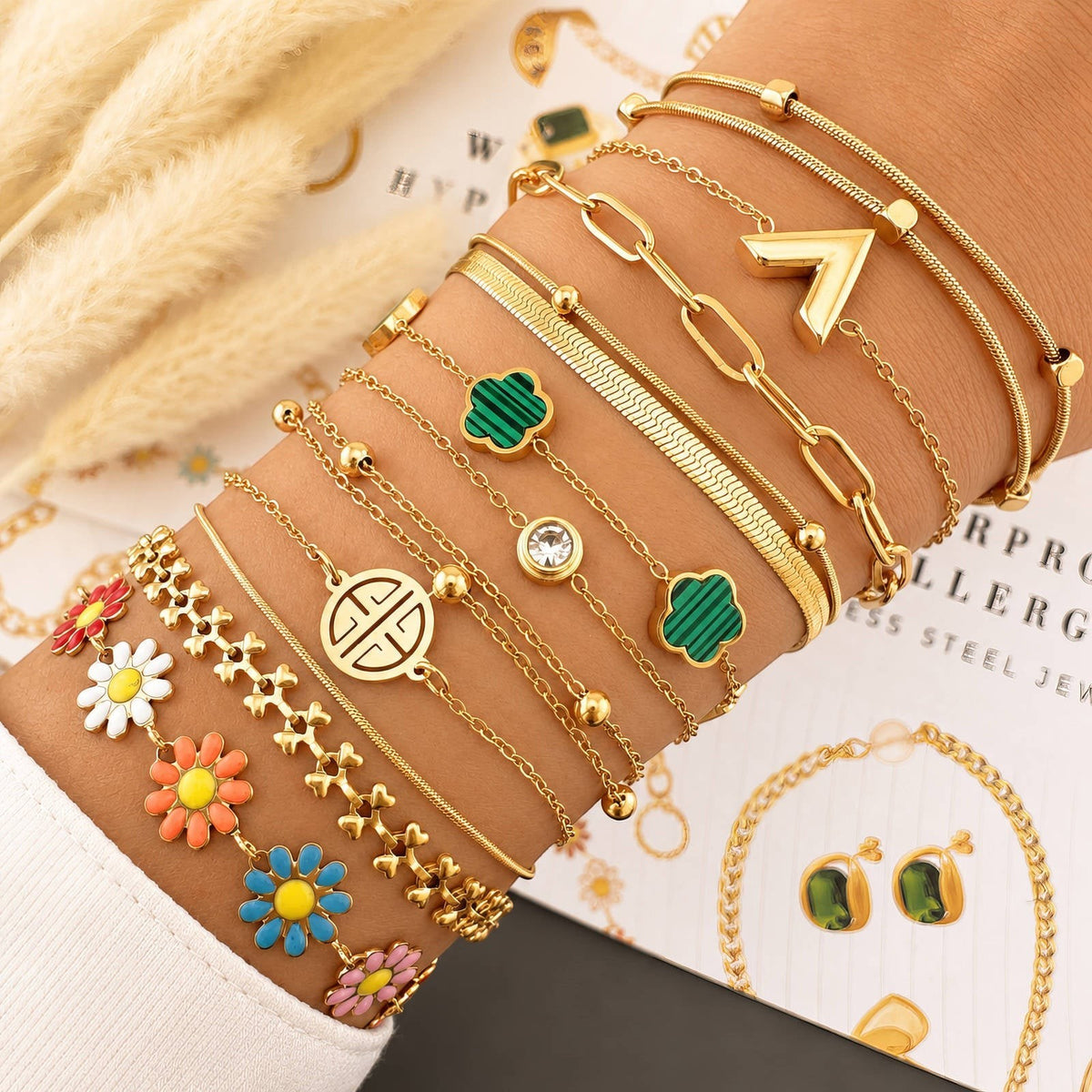 The Velvet Grove gold-tone bracelet stack featuring emerald green clover motifs, floral charms, and delicate link chains.