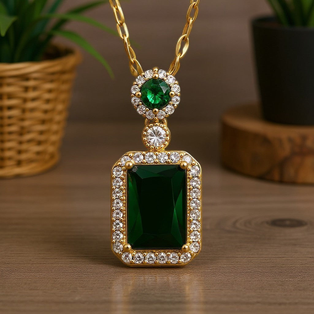 The Velvet Grove emerald-green rectangular pendant necklace with clear crystal accents on a gold-tone chain.
