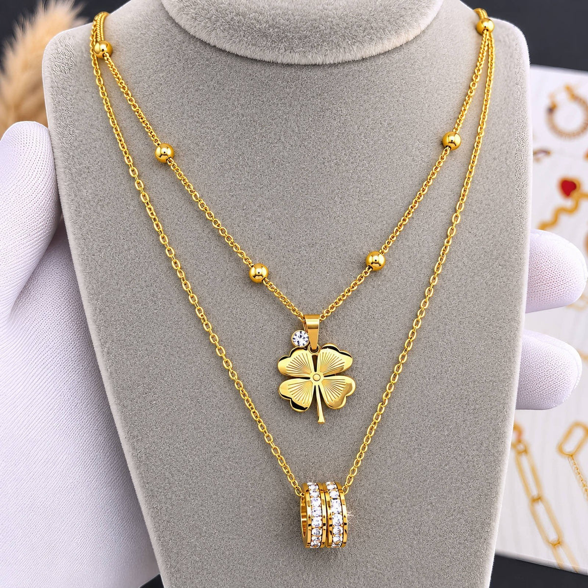 The Velvet Grove gold-tone layered necklace with a four-leaf clover pendant and a pavé-set crystal ring charm.