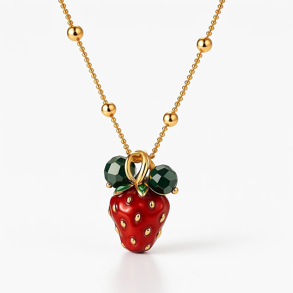The Velvet Grove strawberry pendant necklace in 18K gold plated stainless steel with red and green enamel details.