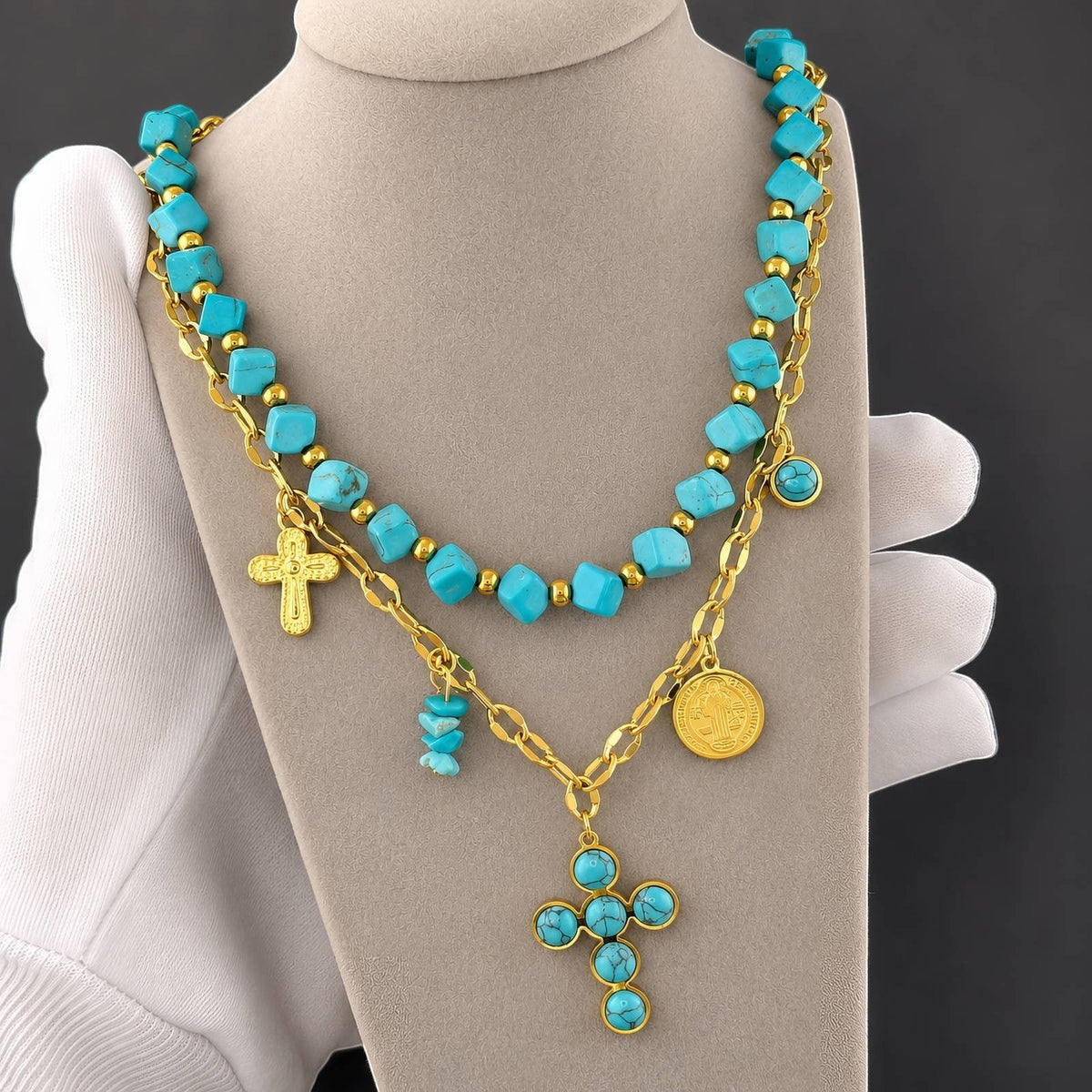 The Velvet Grove layered statement necklace featuring turquoise beads, gold-tone chains, cross charms, and coin pendants.