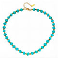 The Velvet Grove beaded statement necklace featuring turquoise-hued beads and polished gold-tone spacers.